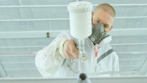 mechanic painting car parts with electric spray gun in garage 4k