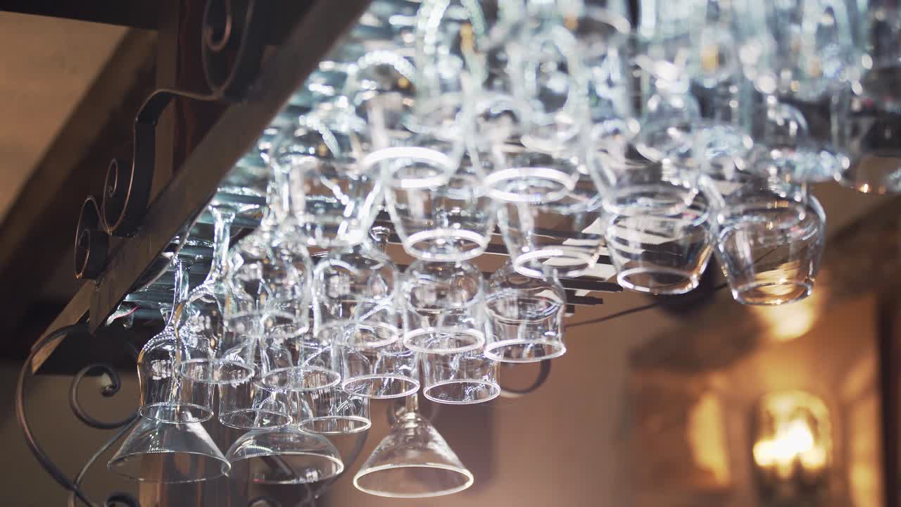 Different glasses hanging from a glassware holder above the bar counter. Clean glasses upside down in a bar