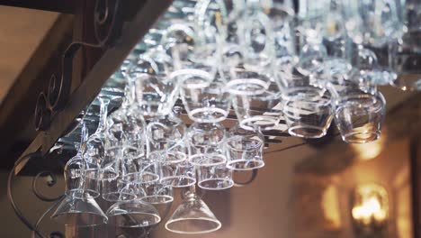 different glasses hanging from a glassware holder above the bar counter. clean glasses upside down in a bar