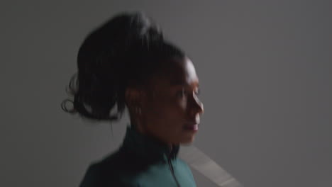 Close-Up-Shot-Of-Head-And-Shoulders-Of-Female-Athlete-Wearing-Tracksuit-Training-In-Gym-Fitness-Class-With-Jump-Rope-Or-Skipping-Rope-Against-Plain-Background