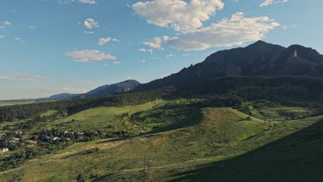 aerial over the forested hills of boulder with the flatirons mountain peaks in the background, colorado, usa