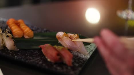 a person sampling sushi from a platter