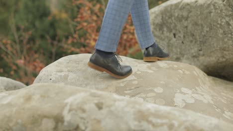 Man-feets-stepping-over-boulders-mountains-near-forest.-Hill-of-a-high-mountain