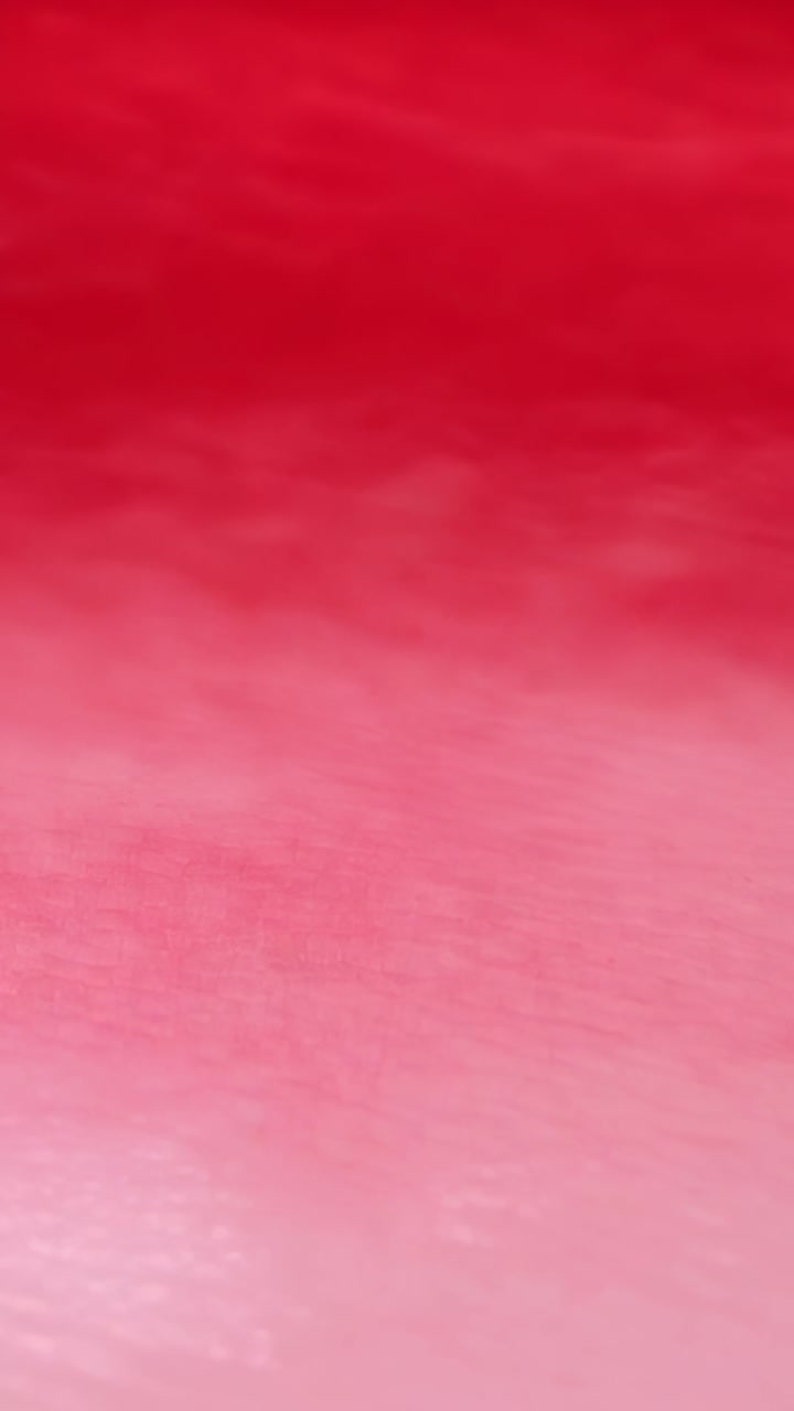 Camera performing slow focus shifts over red-to-pink gradient, revealing subtle texture for design