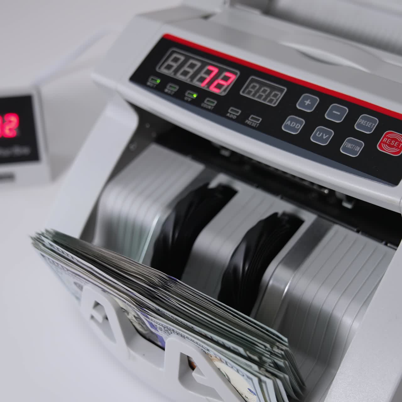 Counting American one hundred dollar bills in the bank equipment. White cash counting machine working. High angle view