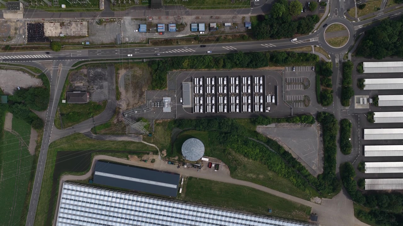 Aerial view of a large battery energy storage system beside a fossil fuel power plant in Germany, showing grid storage, electricity infrastructure and the energy transition.