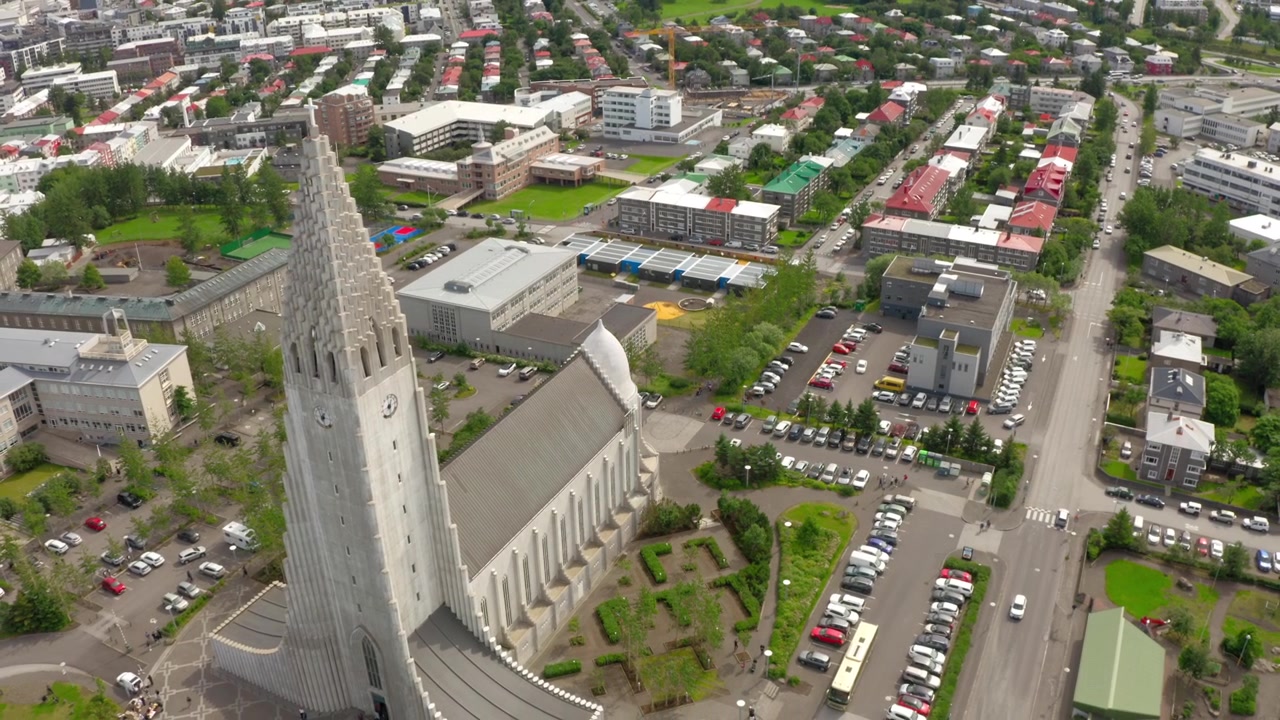 Vista aérea de la famosa iglesia Hallgrímskirkja y la ciudad circundante de Reikiavik, Islandia. El paisaje urbano muestra casas coloridas, calles y estacionamientos