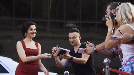 celebrity on red carpet signing autographs for fans and media