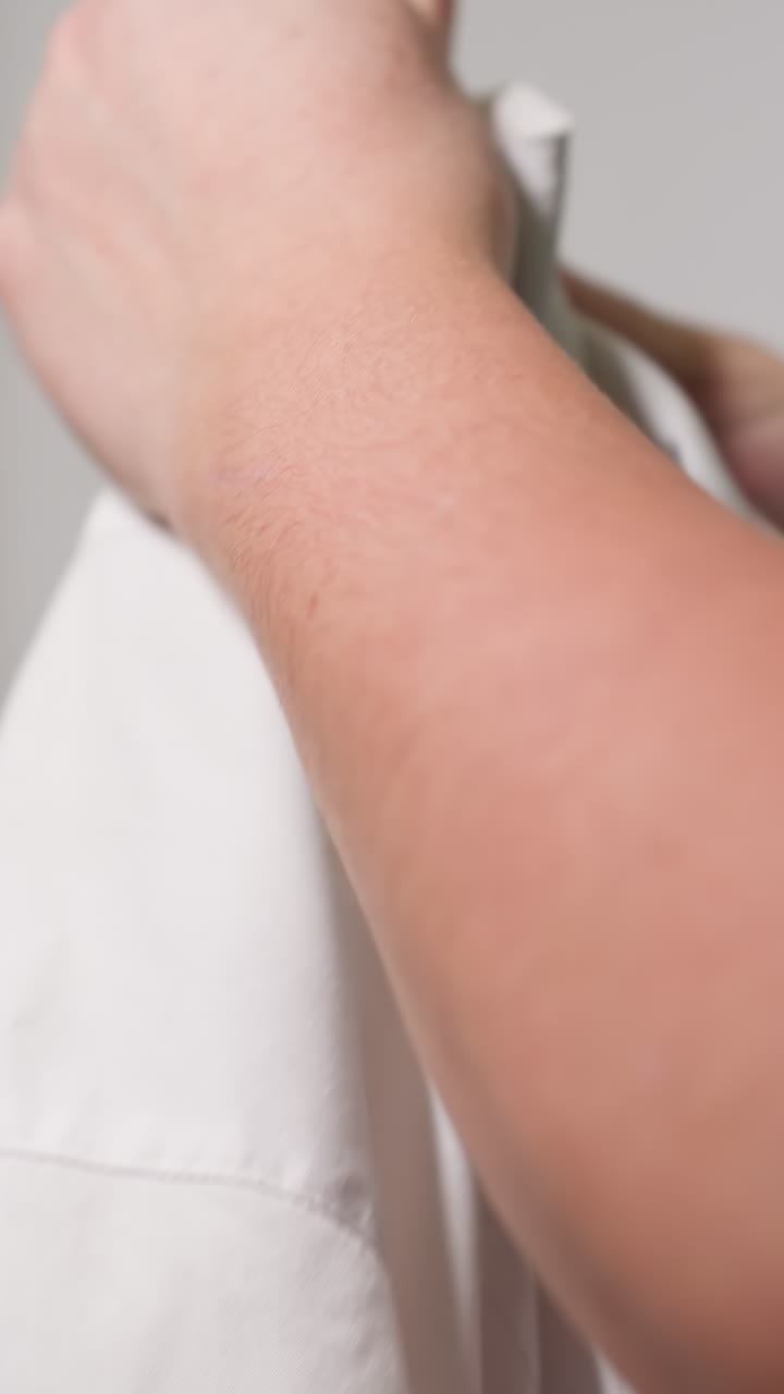 Gentle garment handling, Meticulously arranging textiles on hangers with calm craftsmanship, Carefully smoothing fabric and inspecting seams before gracefully hanging garments for display