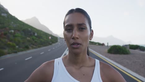 retrato de una mujer de raza mixta haciendo ejercicio en un camino de montaña deteniéndose para descansar durante la carrera