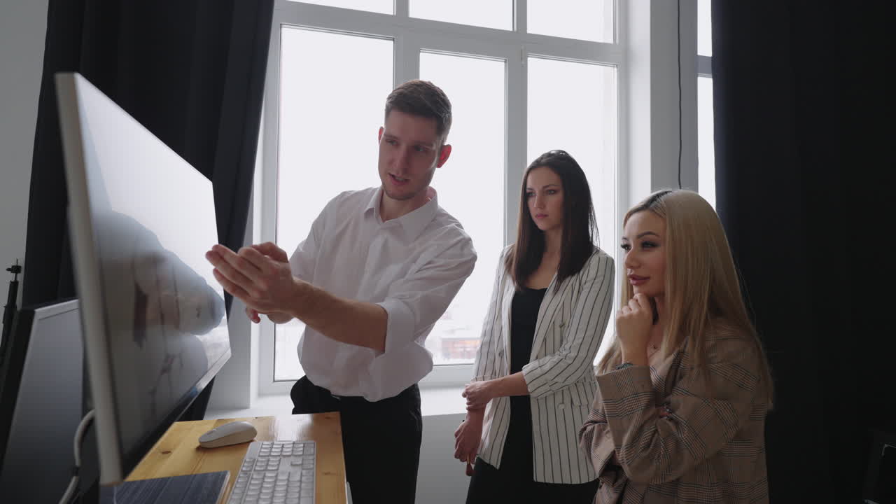 дизайнер, художественный директор, продюсер смотрят фотографии на мониторе компьютера для фотосессии, обсуждают и выбирают лучший для обложки журнала. обсуждают, глядя на монитор