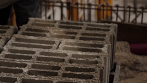 close up of a builder with gloves taking a brick from a pile