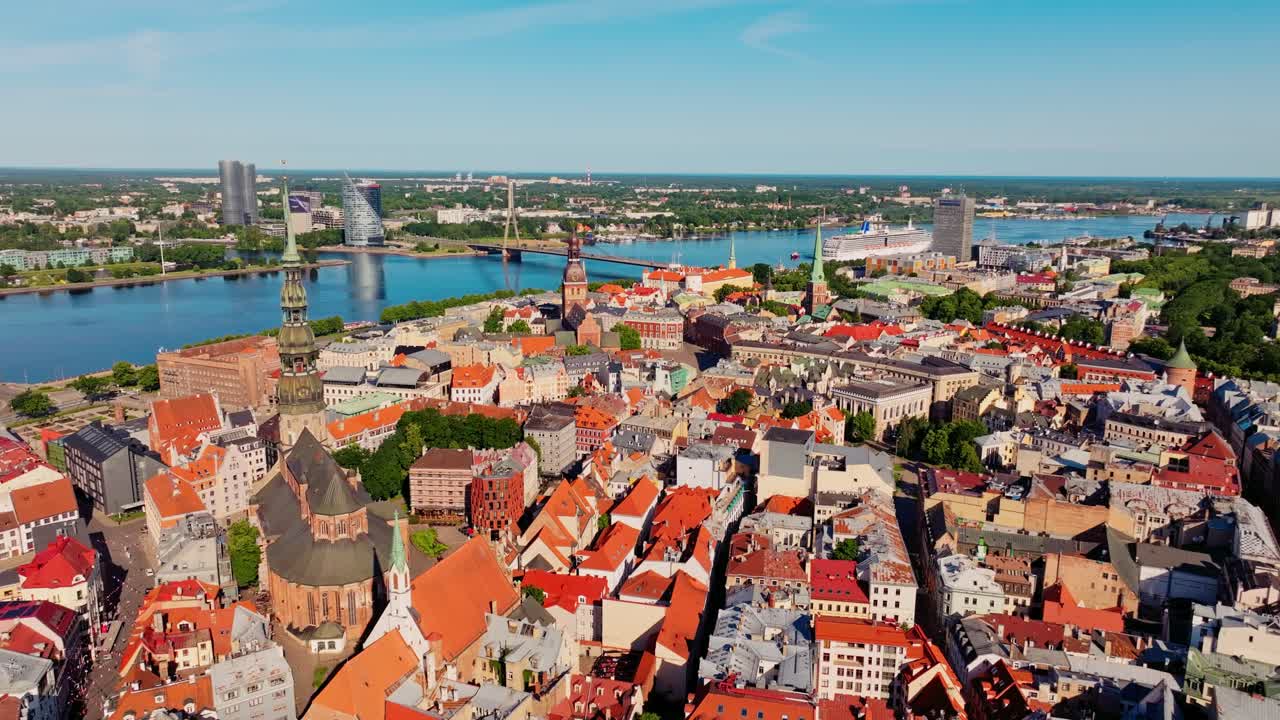 Drone glides sideways revealing Riga old rooftops and Daugava in bright summer