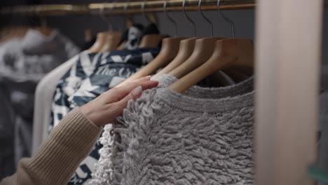 closeup of a woman's hand going through clothes at a clothing store