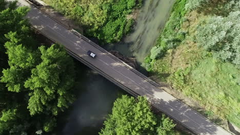 lone car crossing a river bridge in a tropical rural area