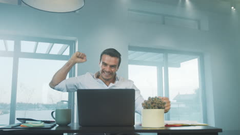 Happy-business-man-getting-good-news-on-laptop-computer-at-remote-workplace