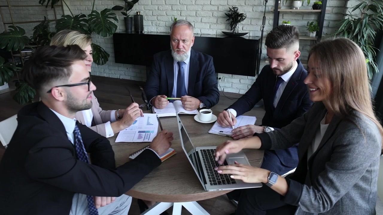 Equipo de negocios diverso colaborando y usando un portátil en una oficina moderna
