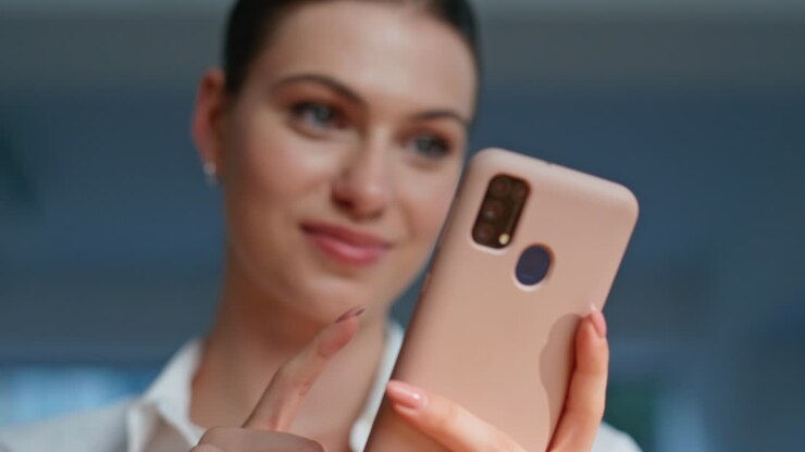 Primo piano di una ragazza allegra che legge un SMS sul cellulare in un appartamento. Brunetta felice che sorride
