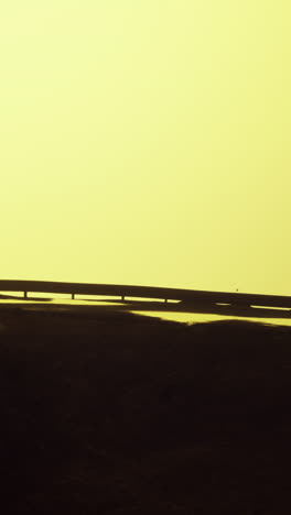 a silhouette of a bridge against a yellow sunset