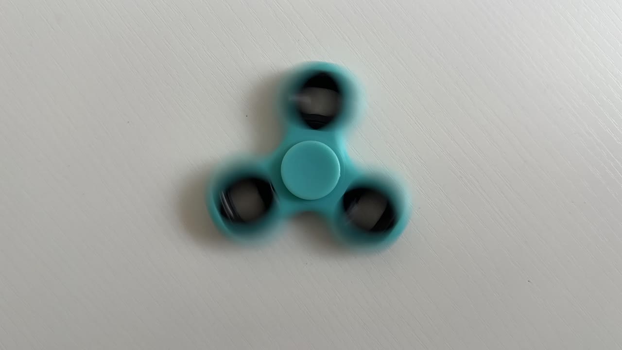 Blue fidget spinner toy gadget spinning on the table