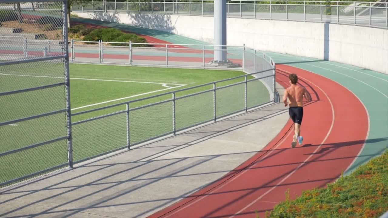 hombre topless con cuerpo deportivo corriendo en pistas al aire libre del estadio