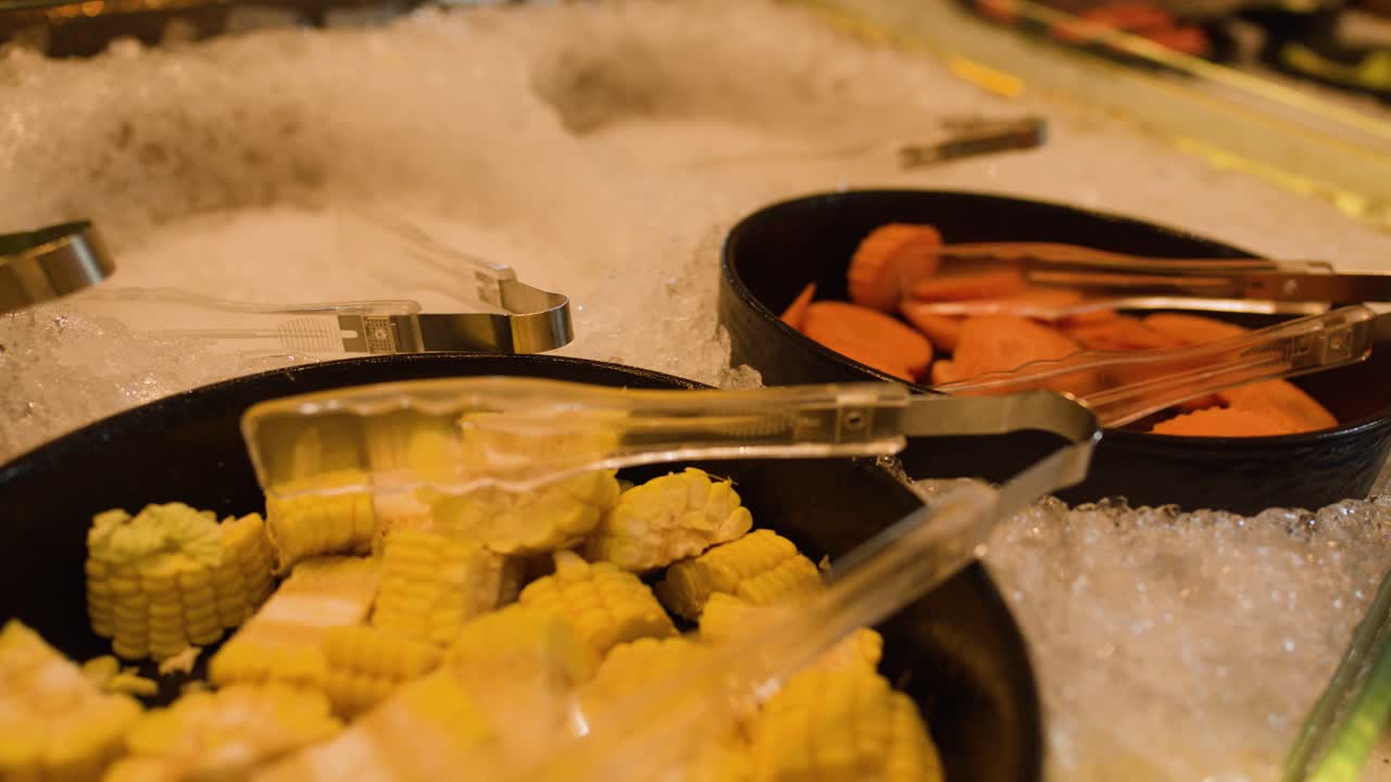 Assorted fresh vegetables and mushrooms on ice at a buffet bar under warm lighting
