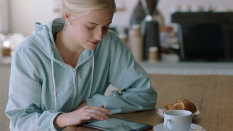 young woman using tablet computer in cafe browsing online reading internet messages relaxing enjoying mobile communication sharing lifestyle on social media close up