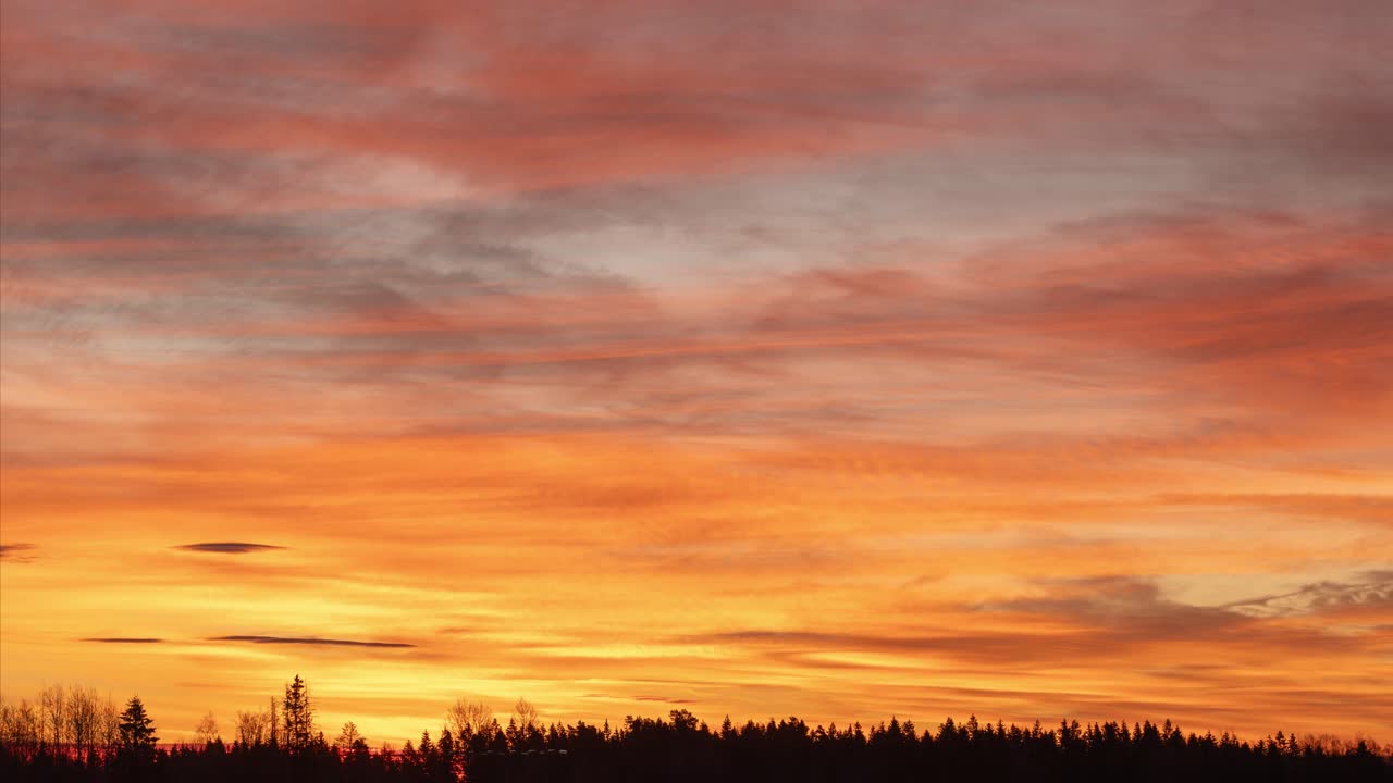 Very colourfull sky and clouds over forest at sunrise. Southern Norway, timelapse video