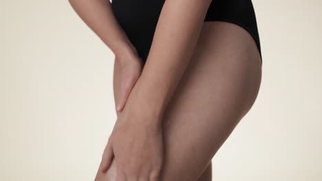 unrecognizable woman in underwear applying moisturizing balm on her leg.