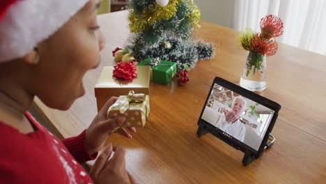 Mujer-Afroamericana-Con-Sombrero-De-Santa-Usando-Tableta-Para-Videollamada-Navideña-Con-Mujer-En-Pantalla