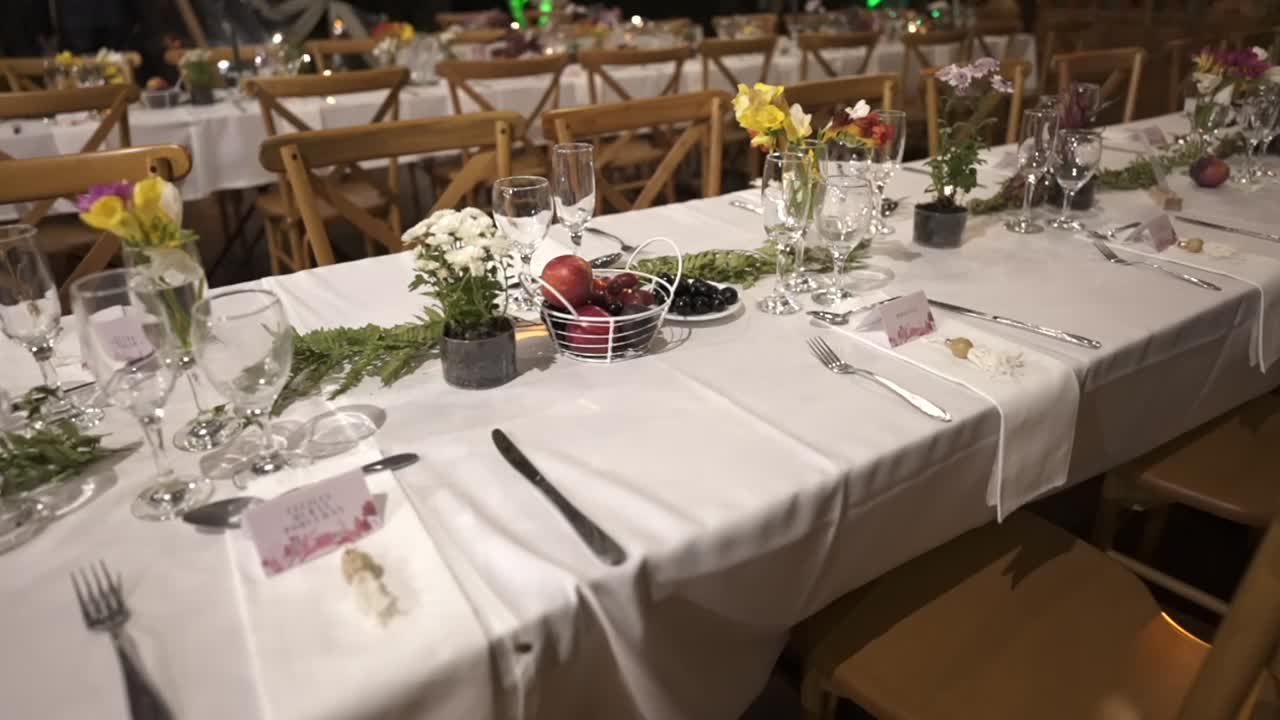 Elegant wedding reception table setting with flowers, fruits, and glassware in a rustic venue