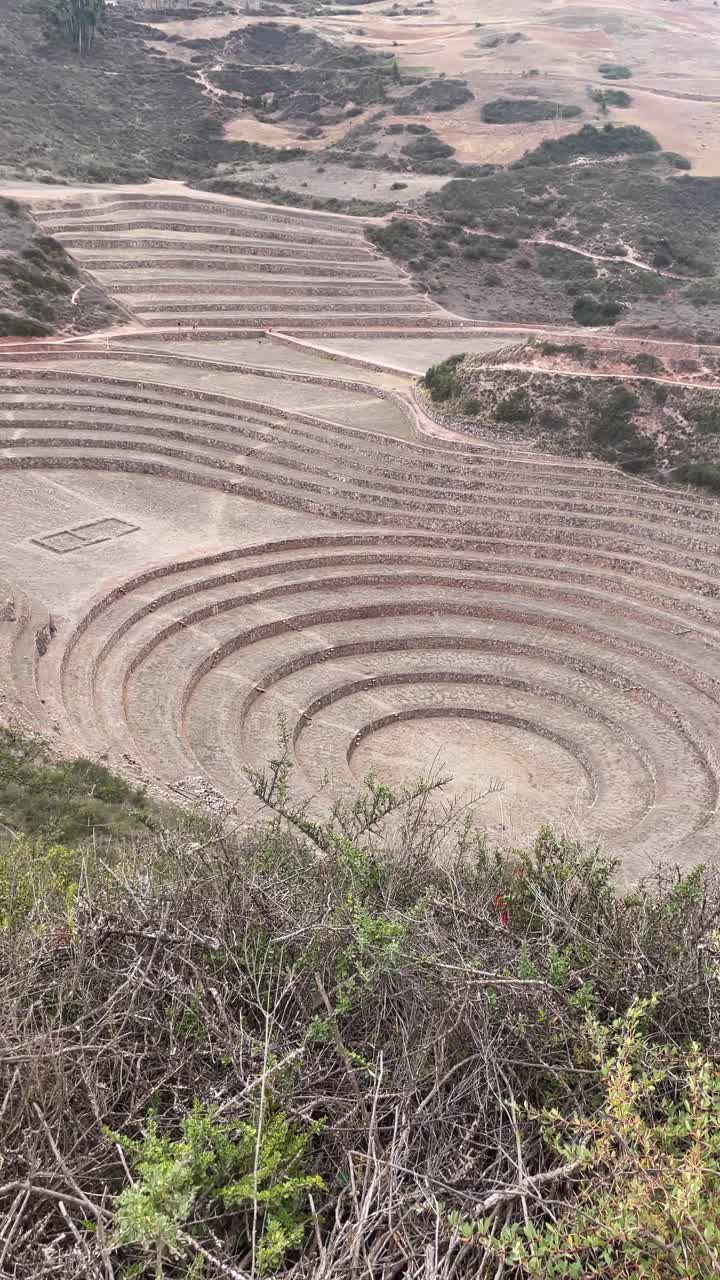Una donna anziana osserva le antiche terrazze Inca di Moray in Perù.