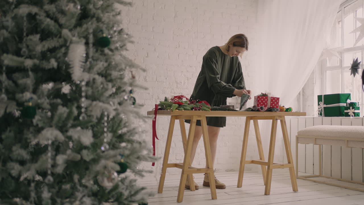 plan general: mujer joven empacando regalos de navidad para sus amigos y familiares cerca de manos femeninas empacando regalos de navidad para amigos. adornos navideños preparándose para la temporada festiva.