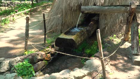 Water-Slowly-Fills-A-Hollow-On-Wood-On-A-Traditional-Korean-Mill-Then-Suddenly-Tips-In-Korean-Folk-Village,-Yongin,-South-Korea