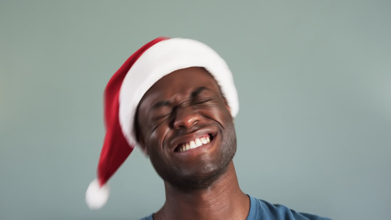Man wearing Santa hat smiling playfully, celebrating Christmas joyfully at home