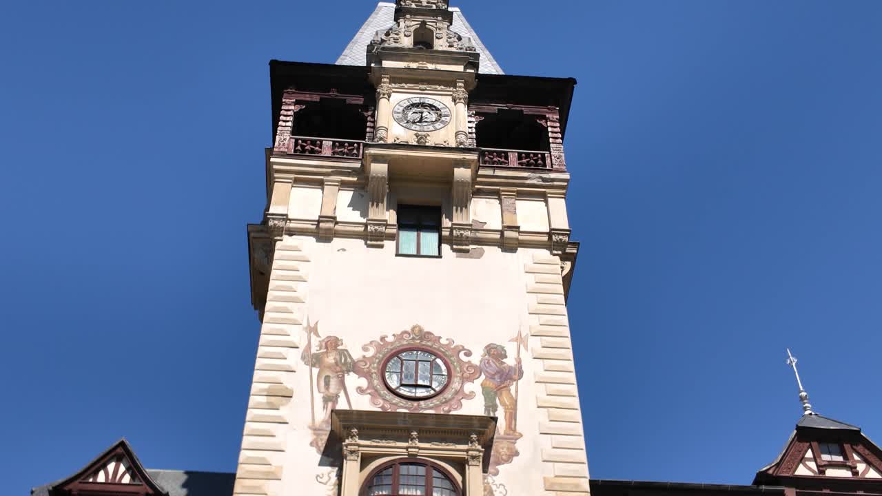 Smooth tilt-up shot revealing the iconic clock tower of Peles Castle in Sinaia, Romania, highlighting its intricate design