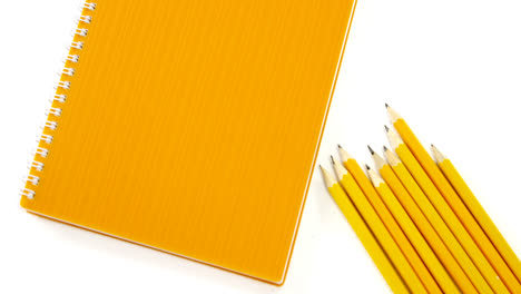 lápices de color amarillo con libro sobre fondo blanco