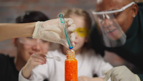 man pours blue liquid into bottle with girl and colleague