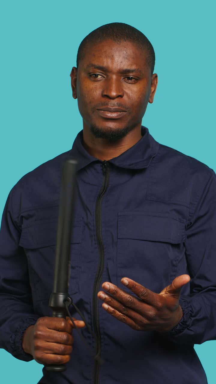 Uomo afroamericano serio in uniforme che tiene in mano un bastone
