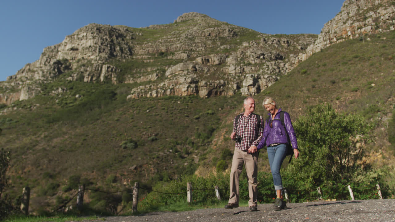 активная старшая пара гуляет по горам