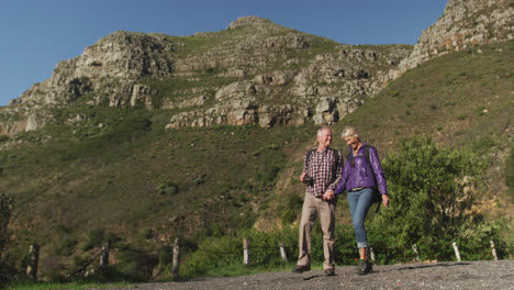 pareja de ancianos activos caminando por las montañas