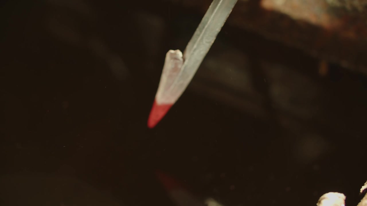 Primo piano di un pezzo di metallo incandescente che viene immerso nell'acqua, causando sfrigolio e sibili, mostrando la forgiatura, la tempra del metallo e l'azione drammatica della fucina