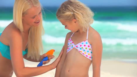 madre poniendo crema solar en su hija