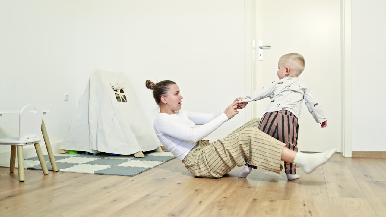 Happy mother amuses her little son, hugs the child. Family games with child, leisure time, motherhood in joy, mother plays active funny game with son