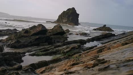 the tide coming in around stones in a pebble beach in broad haven, west wales in early evening