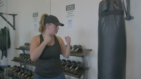 wide slow motion of a young woman punching a punching bag