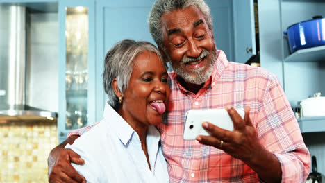 Pareja-Mayor-Tomando-Selfie-Desde-Un-Teléfono-Móvil-En-La-Cocina