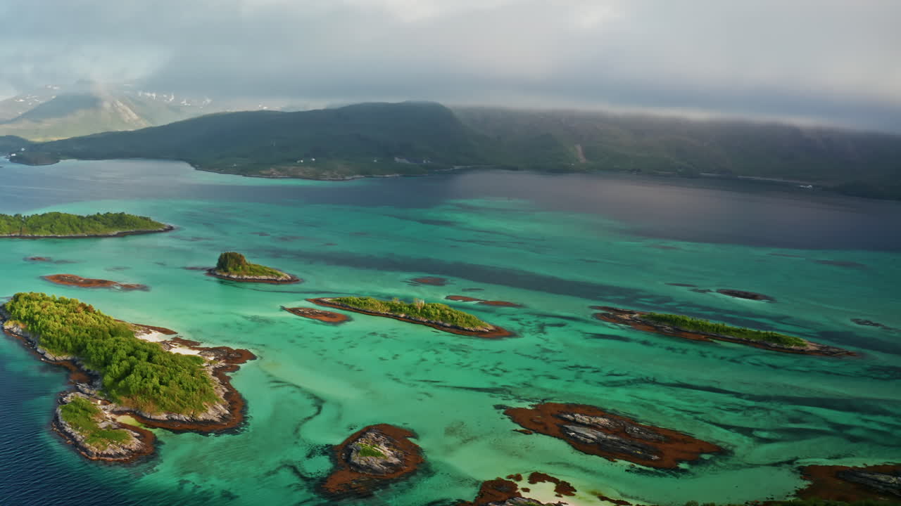 Aerial drone shot over the island of Senja in the Lofoten Ilsands, Norway. High view of the vibrant turquoise sea and the small islands. Breathtaking landscape, untouched natural wonder.