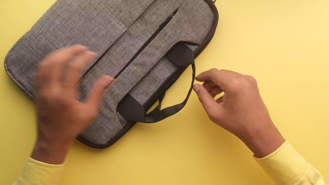 manos abriendo una bolsa de portátil gris