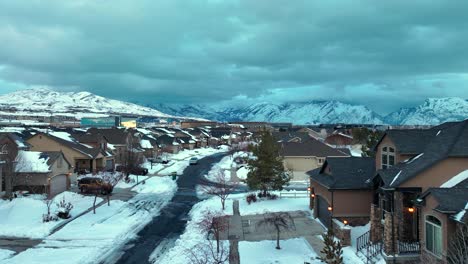 snowy neighborhood at sunrise or sunset below the mountains - aerial flyover